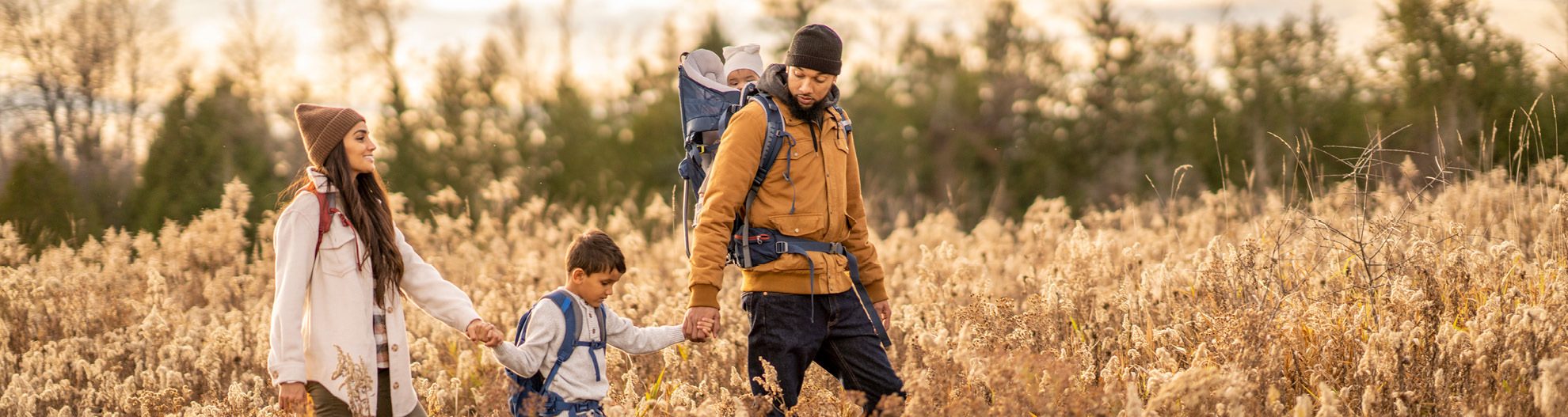 Family of four hiking through tall grass