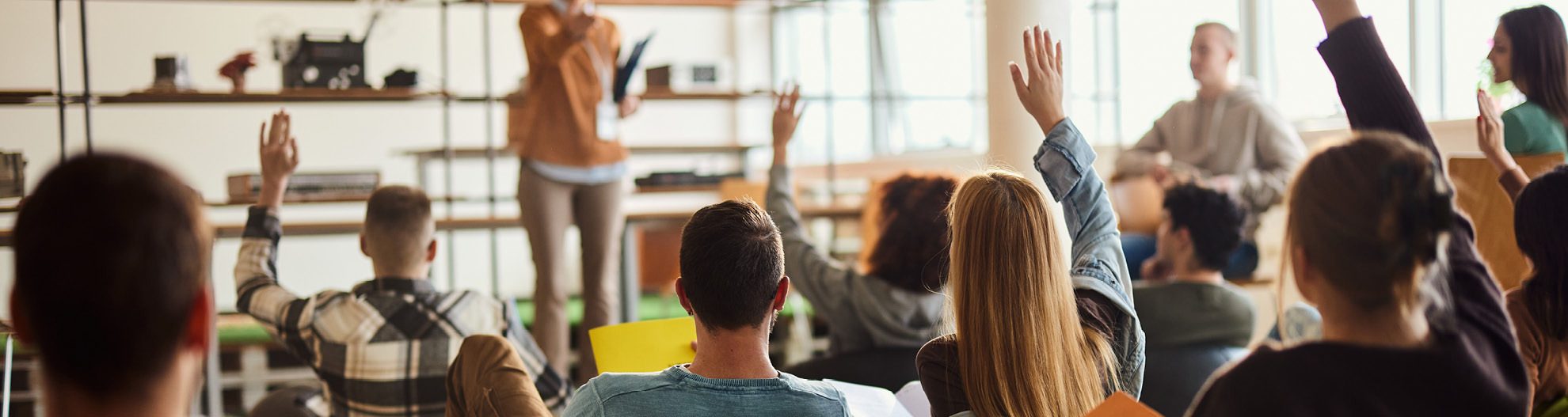 Image of students raising hands in classroom setting